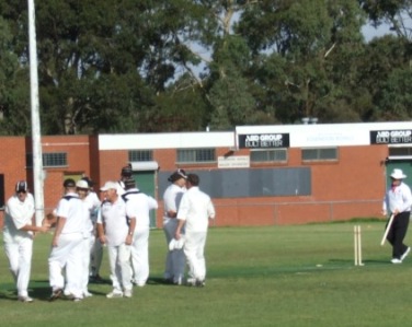The players are all in together for the Premiership huddle, as umpire Peter Gould returns the cartwheeled stump.